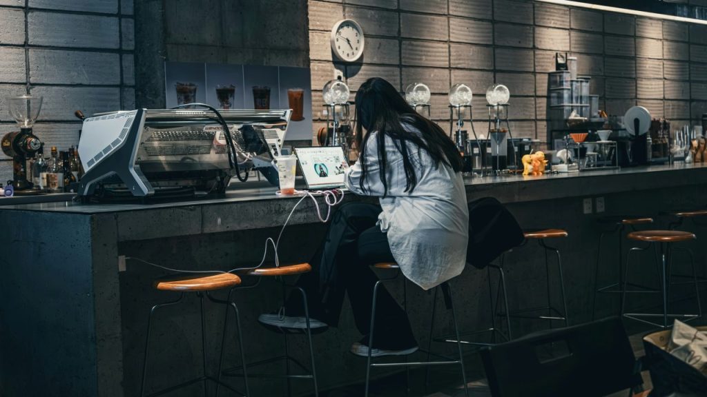Finishing your book isn’t always glamorous: a woman writes at a bar with her laptop.