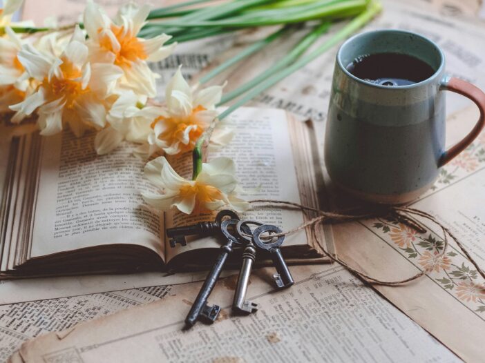 A book with keys resting on it and a mug beside it, symbolizing reflection, resilience, and unlocking the mindset needed to deal with rejection.