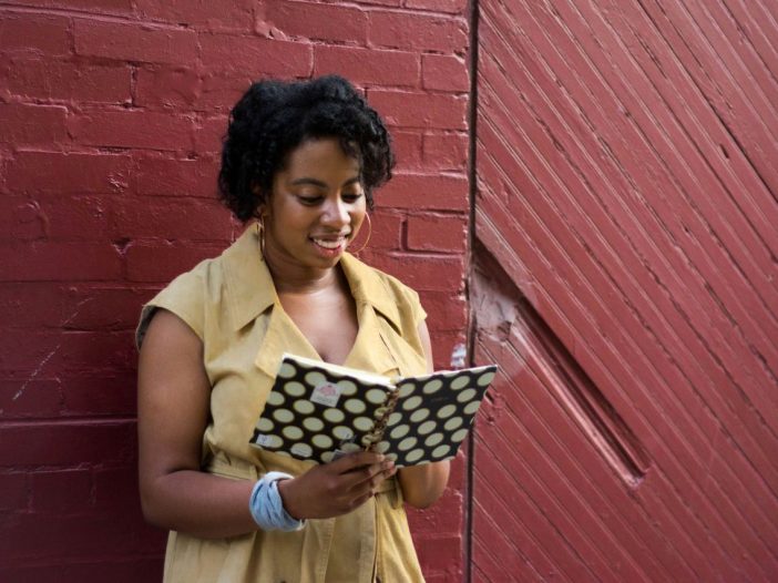 Happy writer capturing the rising action in her notebook.