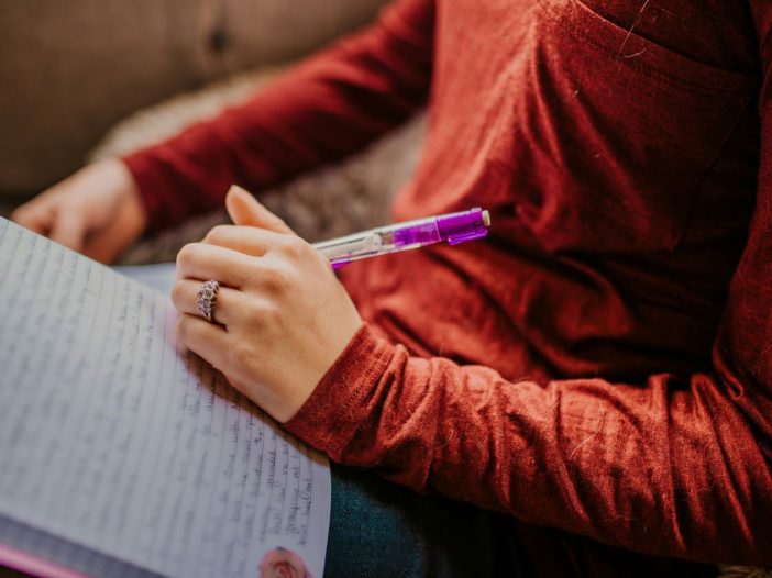 Person in red prepares to capture their best writing tips on paper
