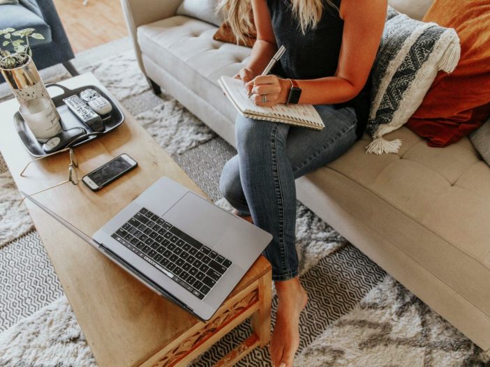 Focused on her next chapter, a writer prepares a book proposal on the couch.