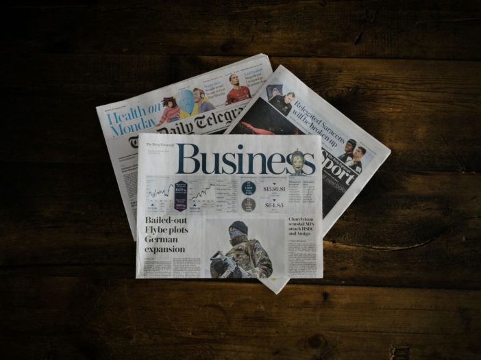 Business journalism in print—stack of newspapers on a desk.
