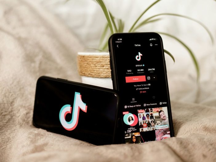 Smartphones on a bed displaying TikTok, ready for a booktok deep dive.